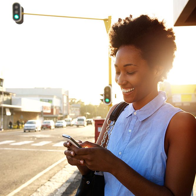 Beautiful african woman using cellphone outdoors Close up portrait of beautiful young african woman using cellphone outdoors in the city